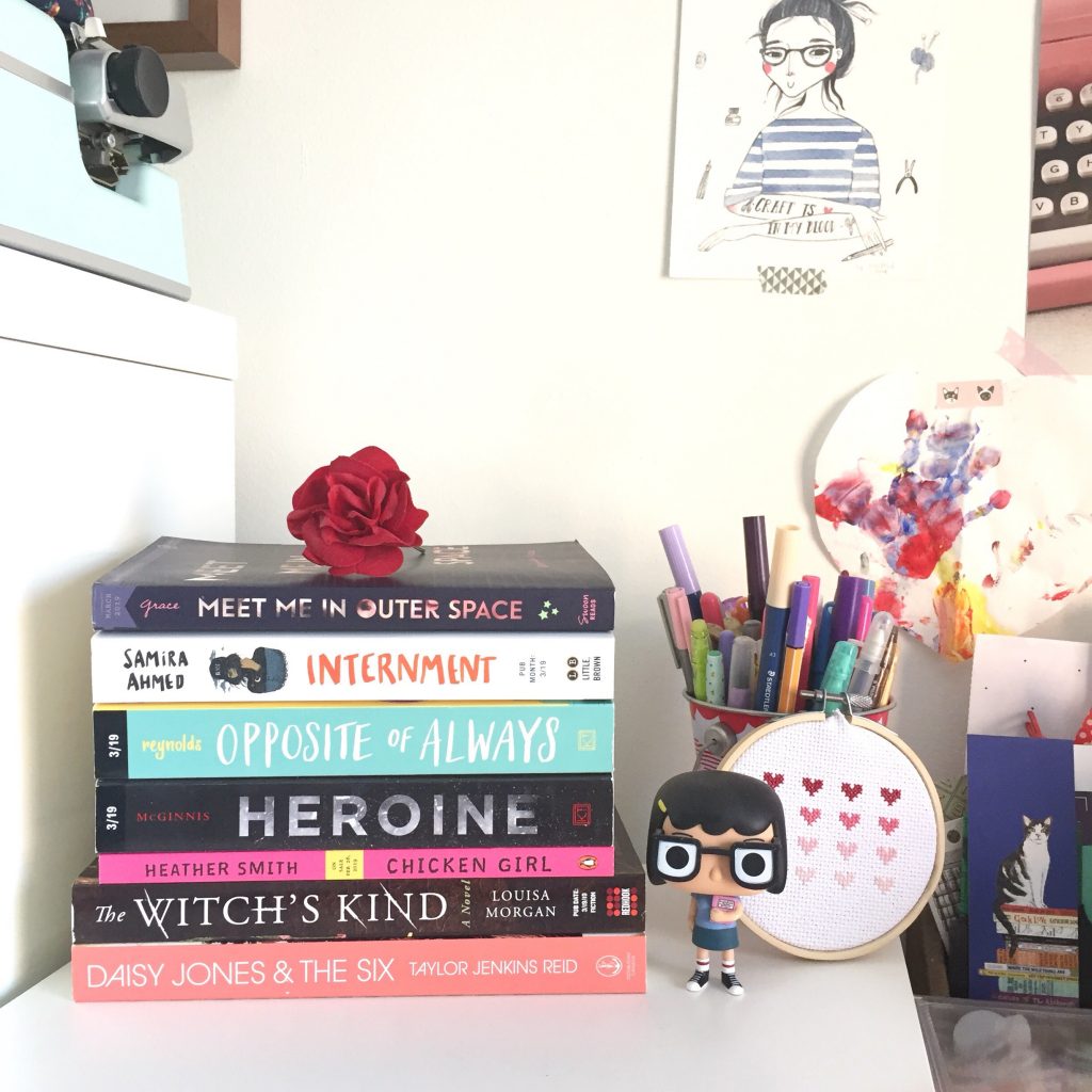 stack of books in an office with stationery and art in the background