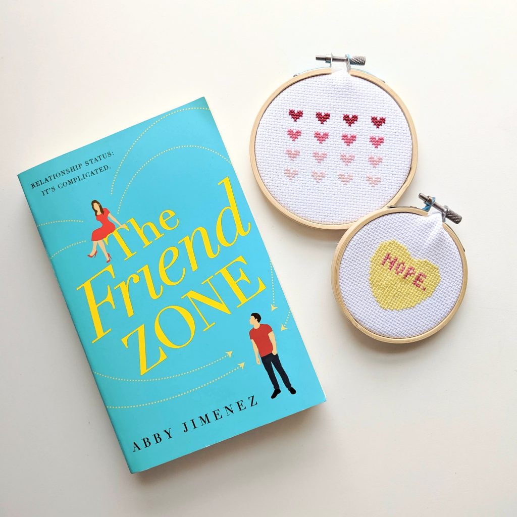Flatlay of The Friend Zone by Abby Jiminez next to two cross stitched hoops