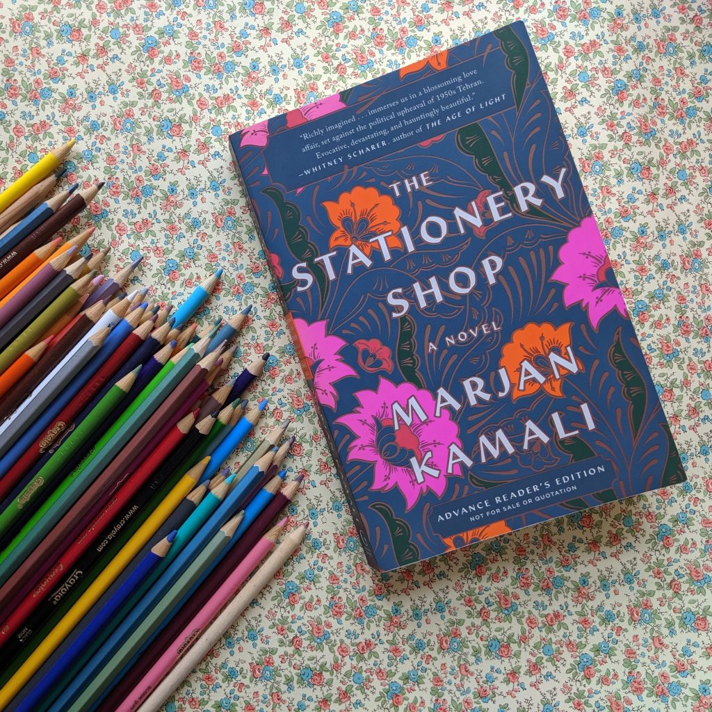 The Stationery Shop by Marjan Kamali next to coloured pencils on a flat lay